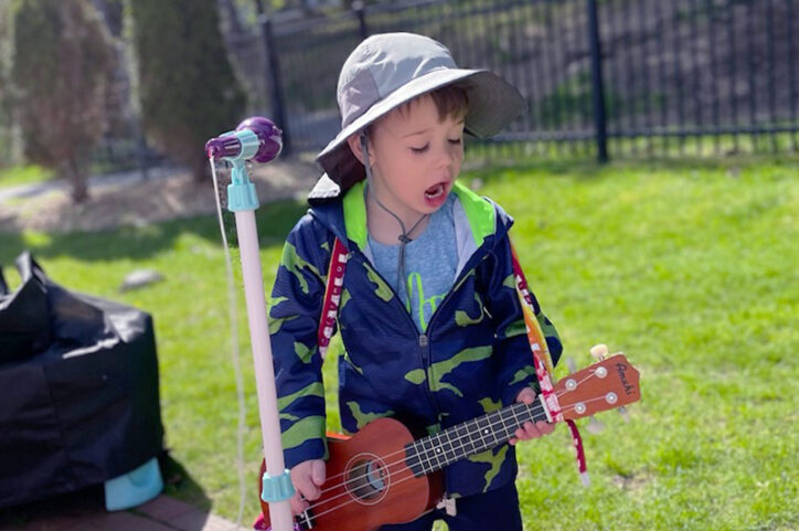 Owen singing in the backyard with a ukulele and play microphone.