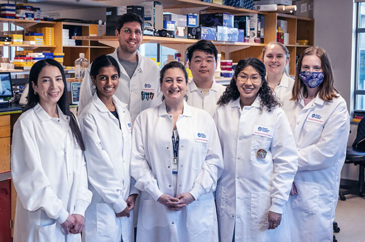 Eight members of a lab team stand for a photograph in a laboratory.