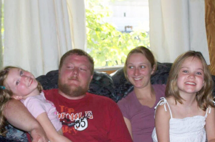 A family sits on a couch, smiling.