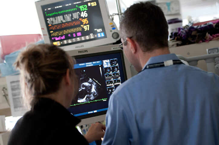 A nurse and cardiologist look at a medical image on a screen.