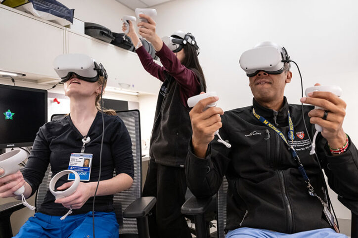 Clinicians wearing virtual reality headsets and holding VR controllers look at a virtual heart.