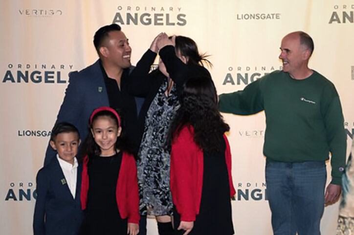 Larry surprised Raul and his family as they posed for a photo at a fundraiser. Raul's mom covers her face with excitement. 