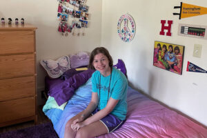 Lindsey sits on the bed of her school's dorm room.