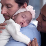 A baby asleep on a man's shoulder