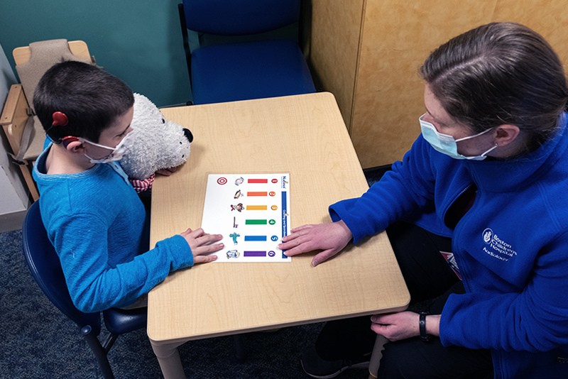 A child with a cochlear implant does language exercises with an audiologist.