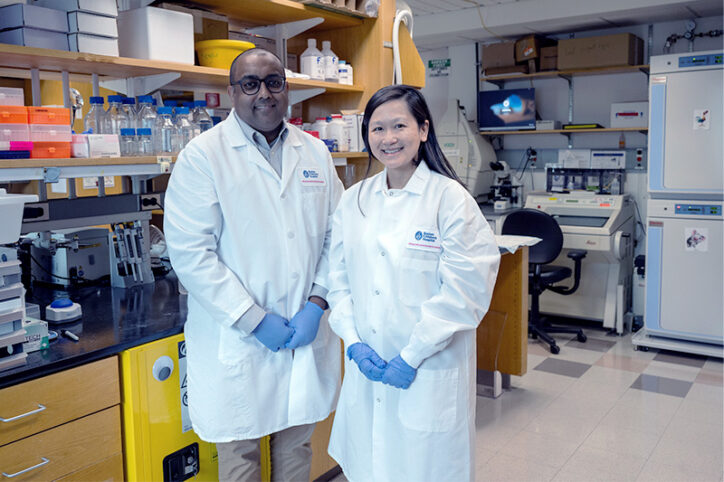 Majmundar and Mann pose in white coats at the lab bench.