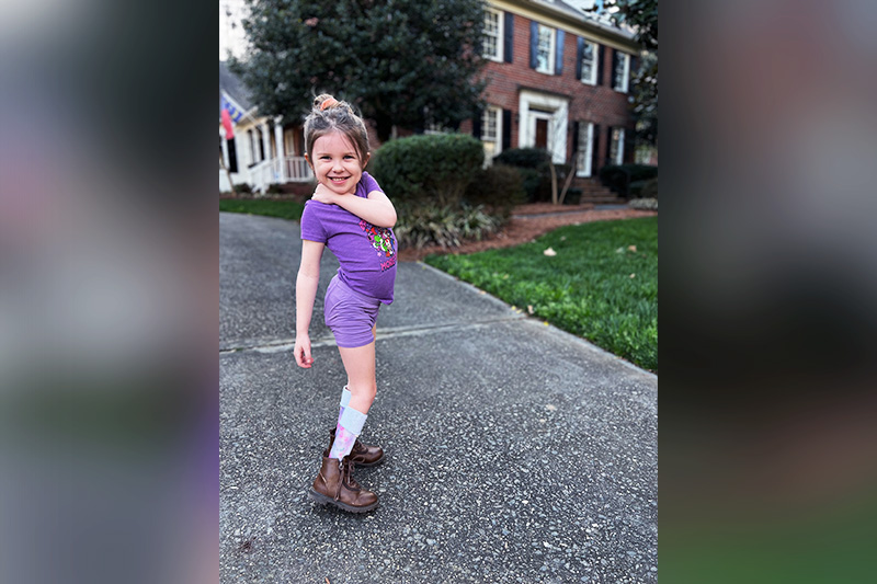 Merritt in a purple shirt standing in a driveway.