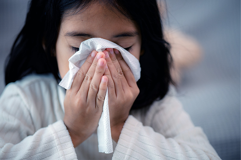 A young girl blowing her nose.