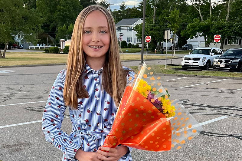 Lily smiles with a bouquet of flowers in her hand.