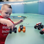 Jack plays with miniature toy trucks on a seating bench.