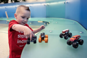 Jack plays with miniature toy trucks on a seating bench.