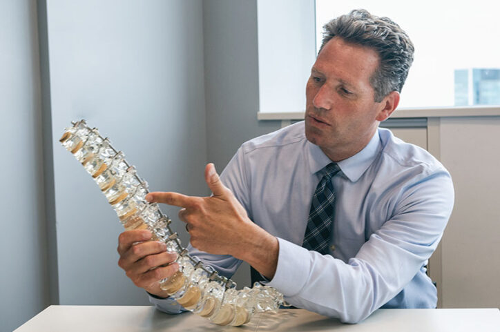 Dr. Daniel Hedequist, orthopedic surgeon who specializes in complex cervical spine operations, with a model of a spine.