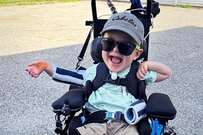 Maxwell smiles and laughs in his wheelchair