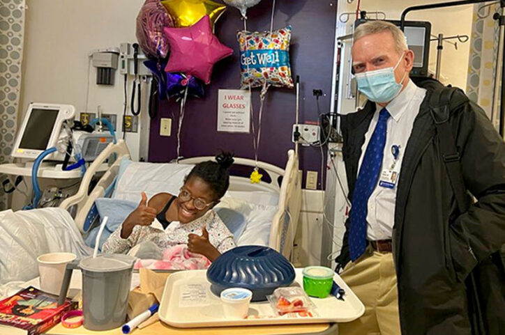 Thelma gives a thumbs up during a visit from Dr. Emans after halo-gravity traction and spinal fusion surgery.