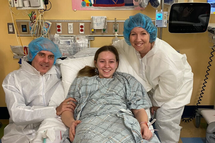 Kiersten's dad, Rob, and her mom, Deirdre, stand on each side of her while she recovers in a hospital bed.