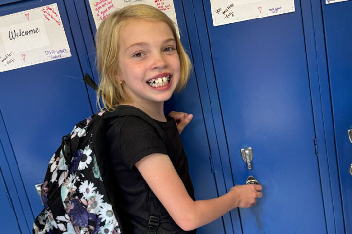 Clara stands before her locker at school.