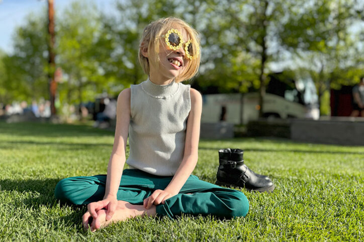 Clara sits outside on grass.