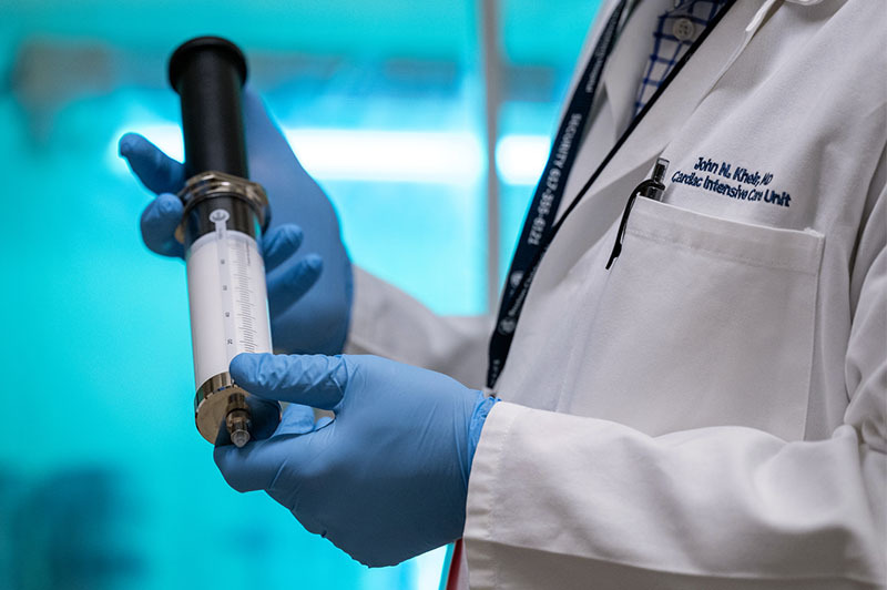 A big syringe, held by a researcher, contains gas microbubbles that aim to deliver emergency oxygen.