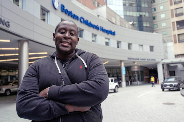 A smiling Branden Baptiste in front of the Boston Children’s Hospital entrance, after his base editing treatment.