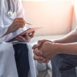 A clinician in consult with a male patient.