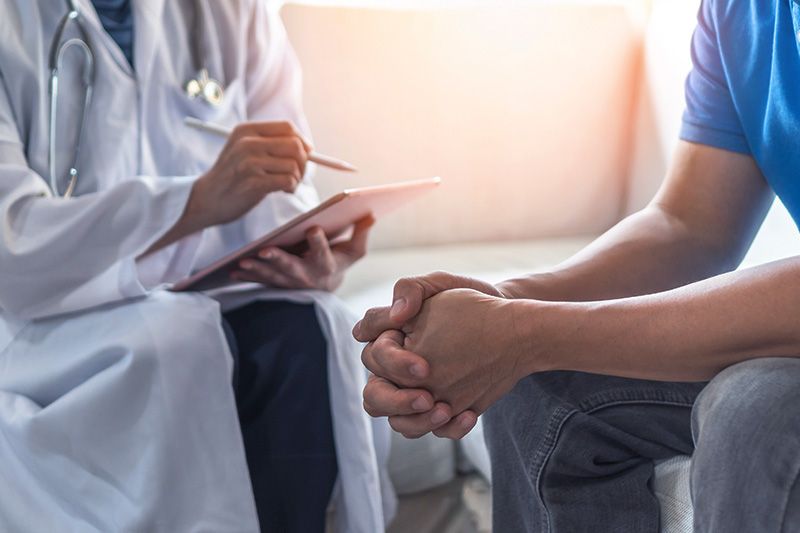 A clinician in consult with a male patient.