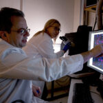 Researchers around a microscope and computer screen.