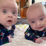 Two babies doing tummy time on a blanket.