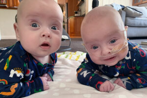 Two babies doing tummy time on a blanket.