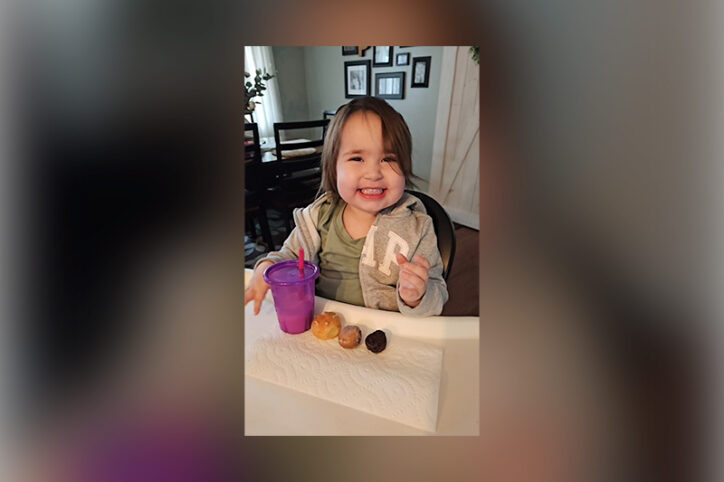 Everly smiles while eating doughnuts with a cup of milk.