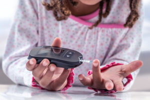 A child with type 1 diabetes testing her blood glucose via finger prick.