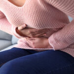 A woman doubled over in pain, holding her abdomen.