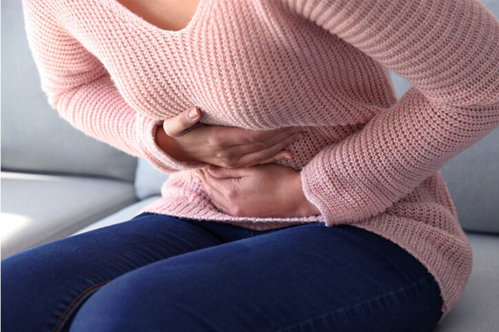 A woman doubled over in pain, holding her abdomen.