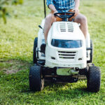 An adult mowing grass on a riding mower.