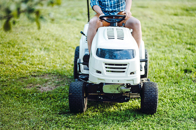 An adult mowing grass on a riding mower.