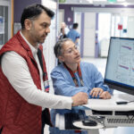 Two doctors review study results on a computer screen.