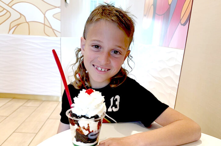 Asa seated at a table in a food court with a hot fudge sundae.