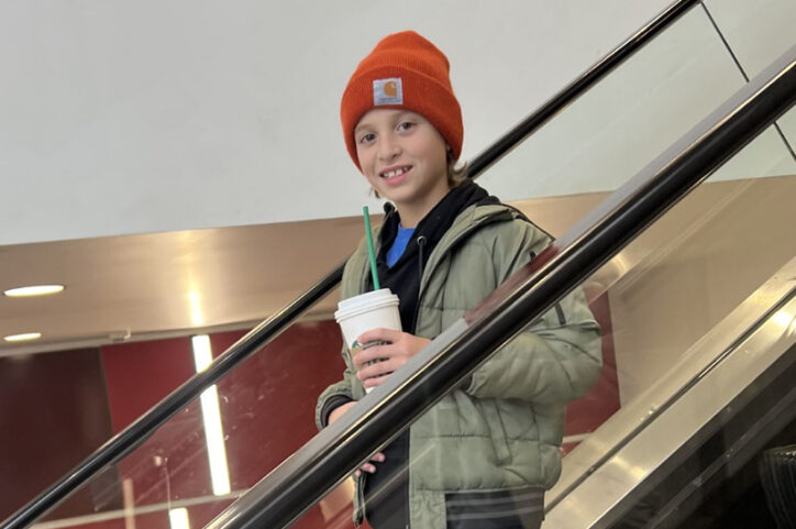 Asa on an escalator in the airport, holding a drink.