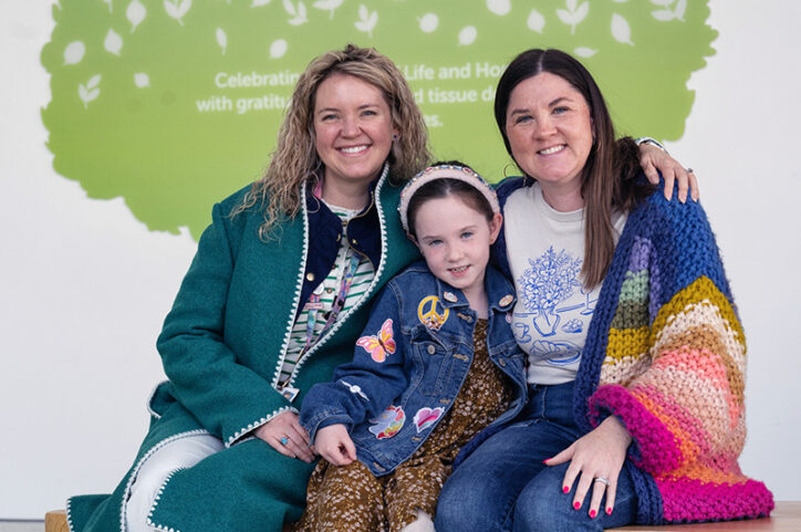 A 6-year-old girl sits between her mother and her doctor. They are all smiling.