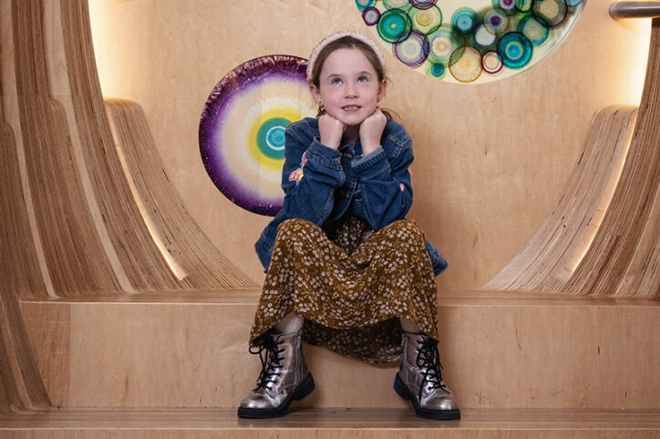 A 6-year-old girl rests her chin on her hands and rolls her eyes playfully.