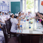 A group of nurses listen to a nurse educator presenting in a classroom.