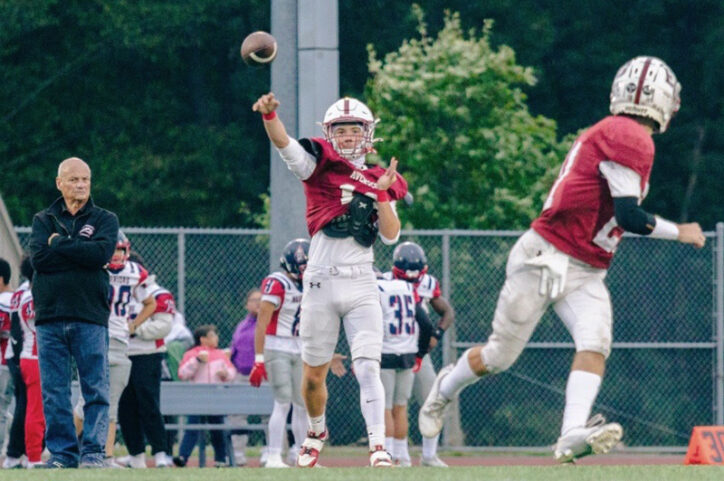 A high school football player throws a warm-up pass before a game.