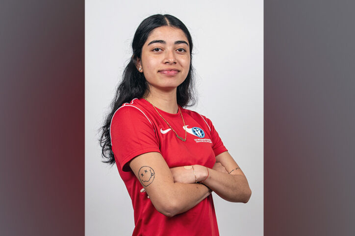 A woman in her early 20s in a soccer jersey.