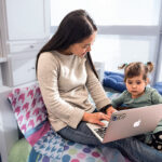 a woman and her young child look at a laptop screen