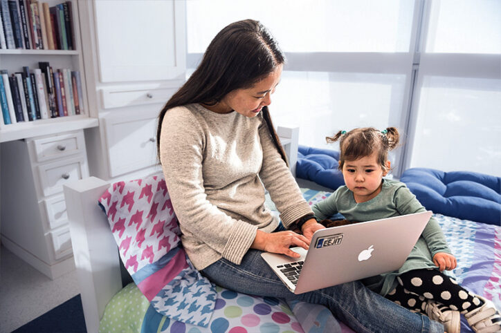 a woman and her young child look at a laptop screen