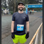 Stephan, a 33-year-old man, stands near the finish line after completing a 10K road race.