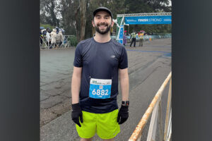 Stephan, a 33-year-old man, stands near the finish line after completing a 10K road race.