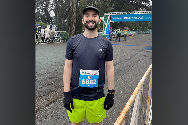 Stephan, a 33-year-old man, stands near the finish line after completing a 10K road race.
