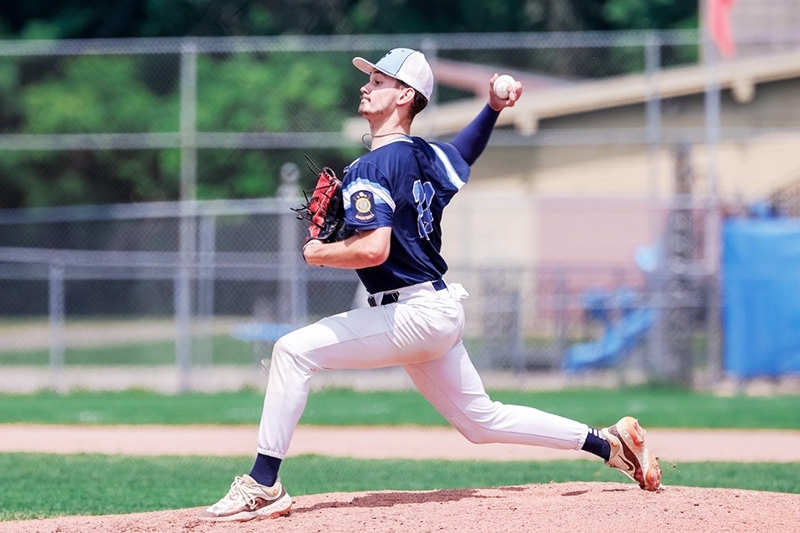 A teen baseball pitcher winds up on the mound during a game.