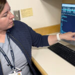 A female physician points to an x-ray image of a patient's knee.