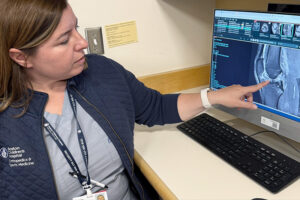 A female physician points to an x-ray image of a patient's knee.